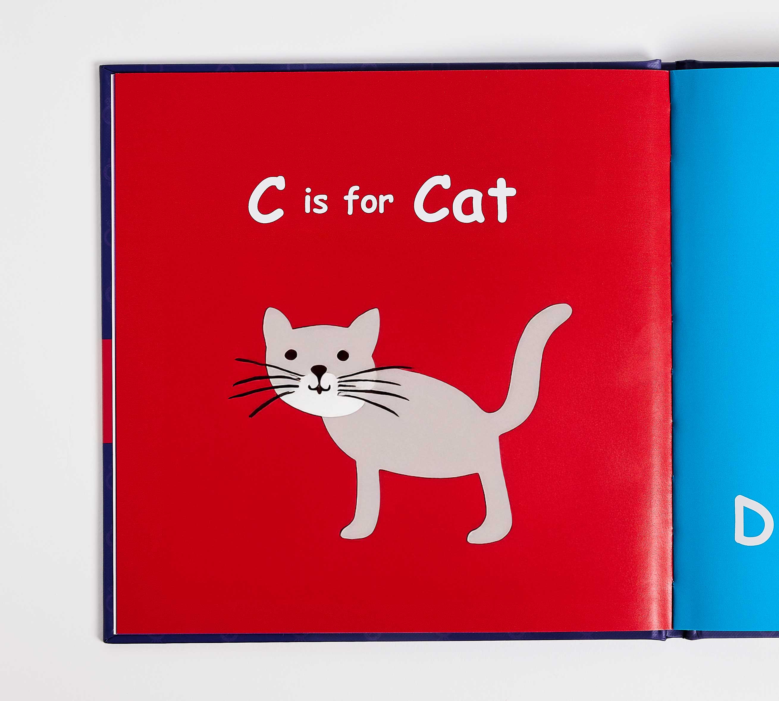 Book page with a red background and a cat illustration, featuring the text 'C is for Cat'.
