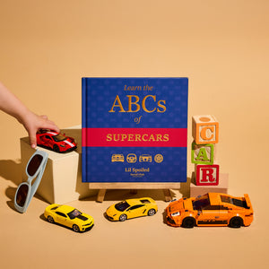 Book titled 'Learn the ABCs of Supercars' with toy cars and colorful blocks on a beige background